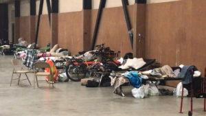 Cots in a shelter with belongings from evacuees