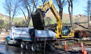 State contractors load debris from a property in Seminole Springs Mobile Home Park destroyed by the Woolsey Fire into a truck for disposal.