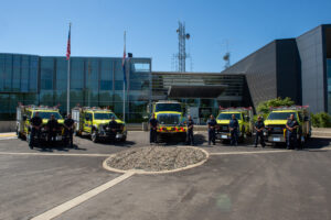 Five fire trucks with operators posed in front of Cal OES Headquarters