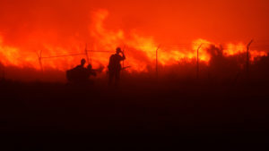 sillouette of two firemen fighting fire