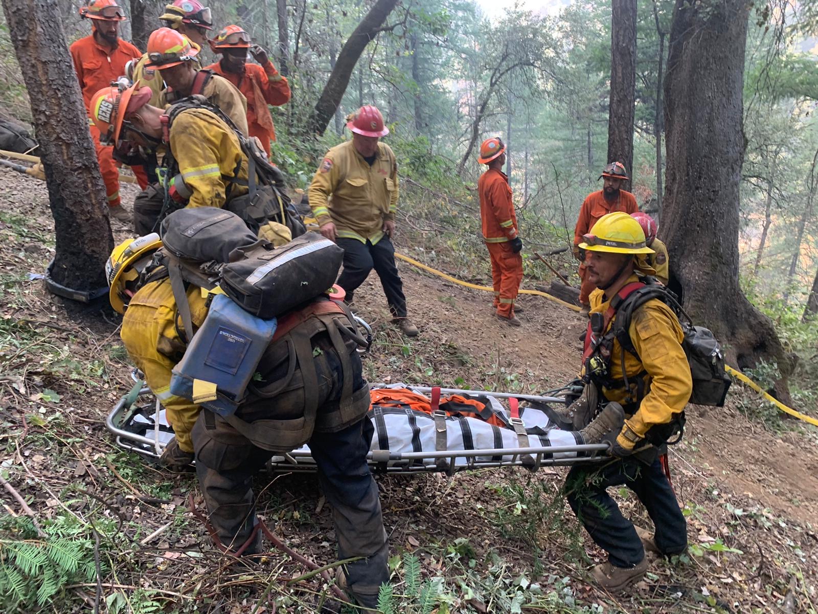 firefighters load injured firefighter into rescue litter basket