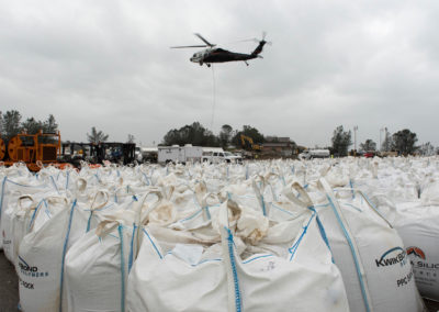 A helicopter prepares to latch onto another bag of rock and material to be delivered to the base of the Lake Oroville emergency spillway.