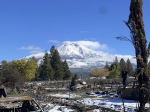 Snowy Mount Shasta in the background. In the foreground are burned cars and other debris for removal.