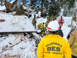 Fire crews respond to an expoded home - fire fighter's jacket reads "CALIFORNIA OES FIRE&RESCUE"