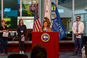 A group of people standing behind a podium with flags behind them
