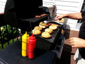 BBQ with mustard and ketchup. There is also meat and buns on the grill