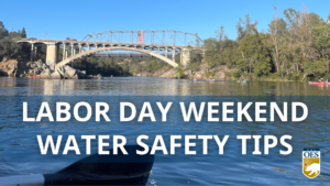 Text reads Labor Day Weekend Water Safety Tips. Background is a lake with kayaks in the background and a bridge. Cal O E S logo in the bottom right corner.