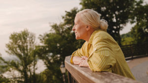 older adult leaning on a deck looking out into distance