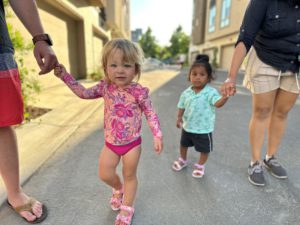 Two Children holding parent's hands in swim suit.