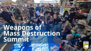 Group of first responders gathered around during an exercise. Text reads Weapons of Mass Destruction Summit with Cal OES logo in the right corner