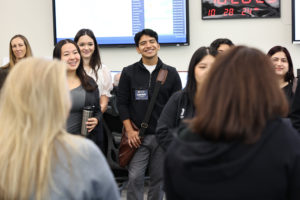 Four people smile broadly as they listen to a woman speak.