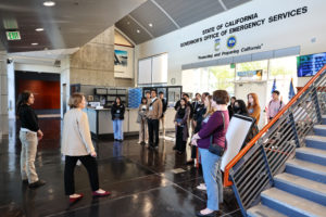 A woman greets a group in a lobby.