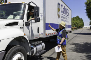 A Cal OES employee gives a thumbs up to the driver of a Cal OES logistics truck.