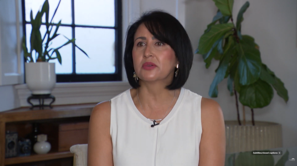 Aurora sitting, wearing a white blouse